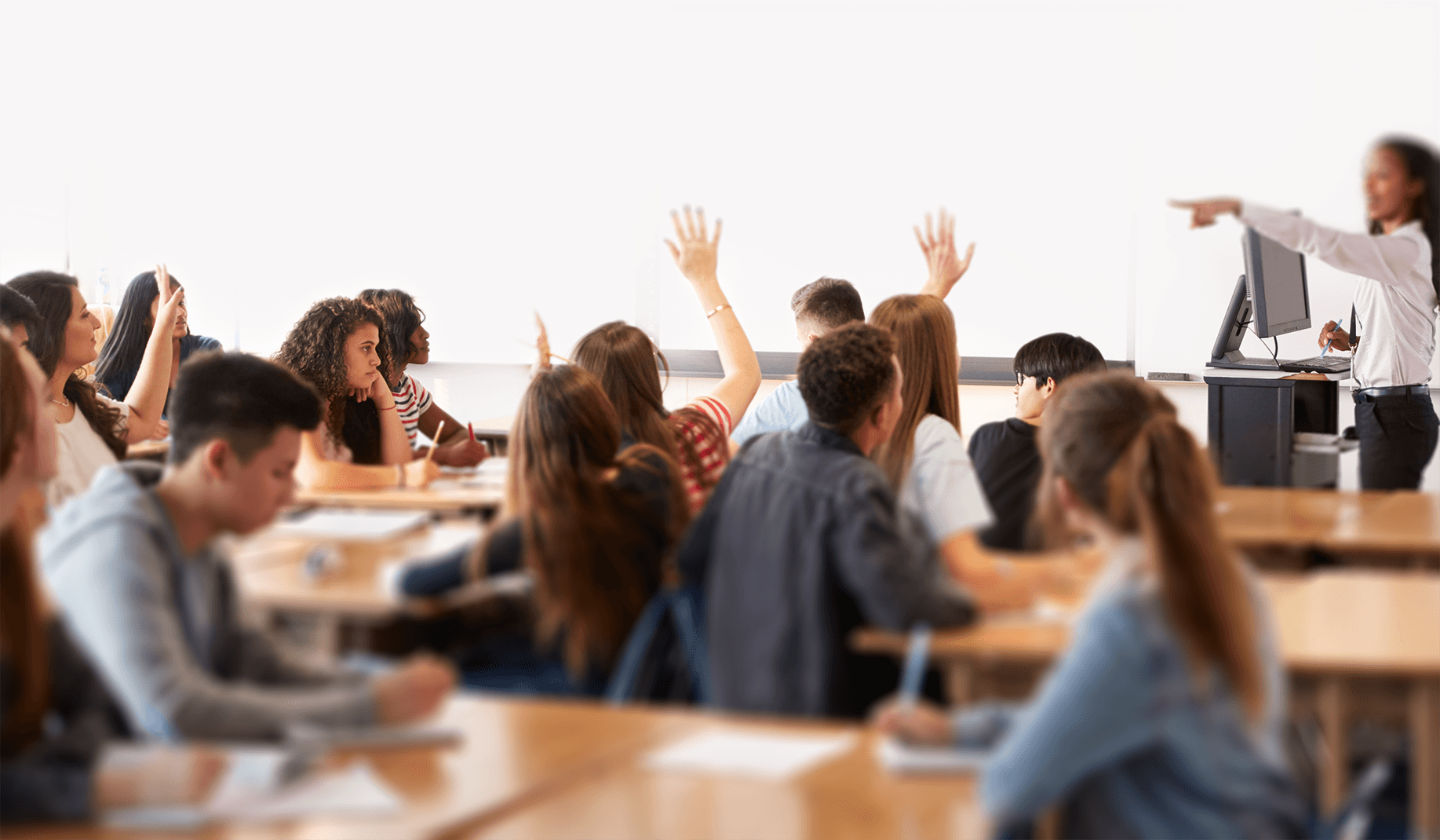 Teacher in a classroom with youth raising hands